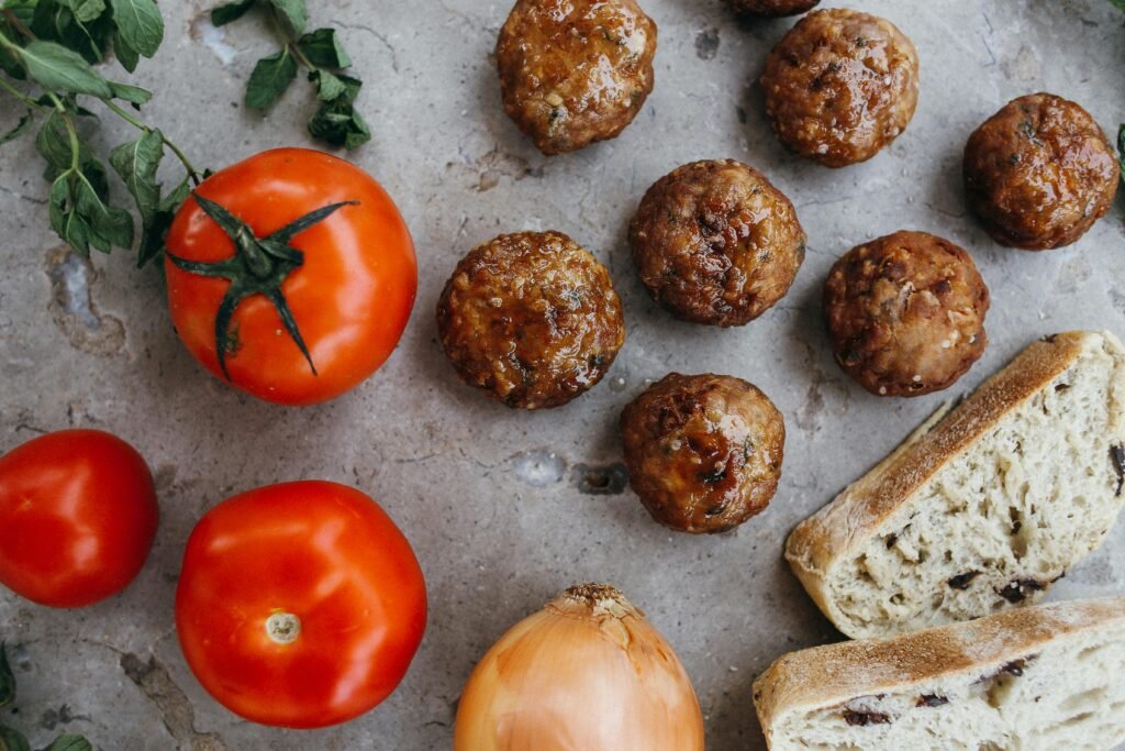 Appetizing flat lay of meatballs, tomatoes, and bread, perfect for culinary inspiration.